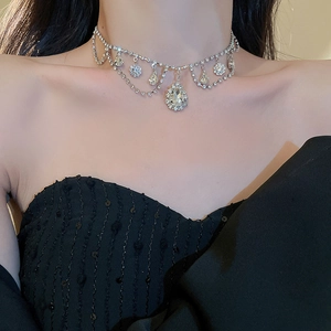 Close-up of layered silver choker necklace with teardrop diamond pendants on model