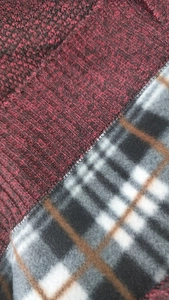 Detail of burgundy knit fabric with thick checkered fleece lining for winter warmth