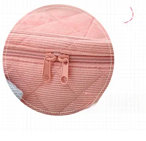 Detail of pink corduroy makeup bag featuring quilted texture and dual zipper closure