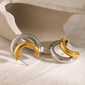 Detail of high-polish C-shaped earrings with two-tone gold and silver finish