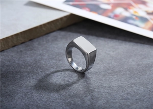 Detailed close-up of a silver rectangular signet ring with a brushed metallic texture