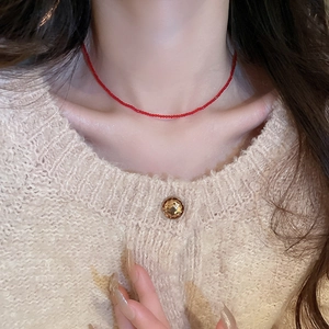 Detailed view of a minimalist thin red crystal beaded choker necklace on a model's neck