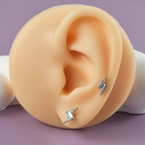 Silver lightning bolt ear studs with opal and zircon crystals on silicone ear model