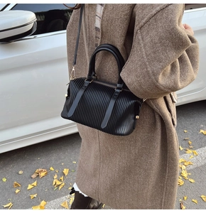 Close-up of black pleated texture faux leather handbag with elegant gold metal zipper