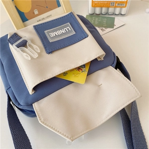 Detail of blue and white nylon crossbody bag with LUNSME logo and plastic buckle