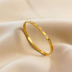 Detailed view of a polished gold titanium steel bangle with six sparkling inlaid zircons
