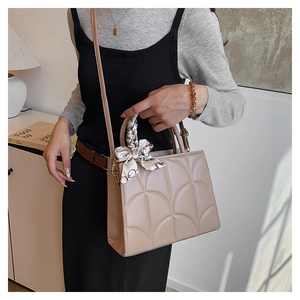 Detail of beige tote bag featuring arched quilted texture and chic printed silk scarf handle