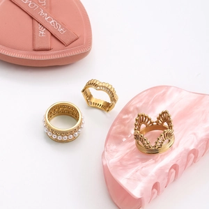 Close-up of 18K gold plated lace crown ring set with white pearl on a pink display