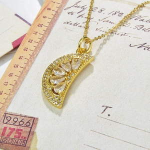 Close-up of gold-plated watermelon slice pendant with clear zircon on vintage letter