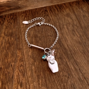 Detail of silver bear bracelet with white cat charm, zircon accents on wooden background