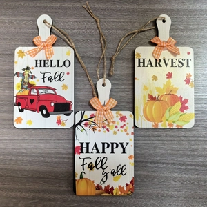 Detail of three autumn wood signs with pumpkin patterns and orange plaid bows for fall decor