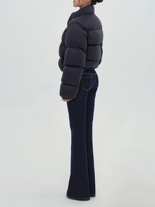 Side view of slim fit dark blue flare jeans and a cropped black puffer jacket on a model