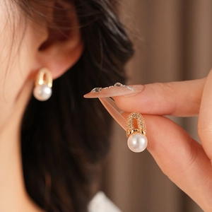 Détail de boucles d'oreilles élégantes en plaqué or en forme de U avec zircon et perles