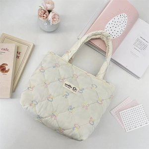 Close-up of quilted canvas tote bag with colorful butterfly embroidery and branded woven label