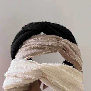 Three twisted fabric headbands in black, beige, and cream with frayed texture details