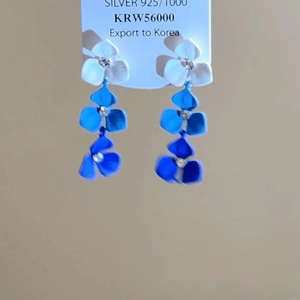 Détail de boucles d'oreilles à fleurs bleues dégradées avec clous en argent 925 et cristaux