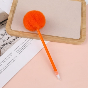 Close-up of a creative orange ballpoint pen with a soft plush pompom on a pink background