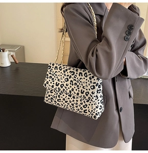 Close-up of leopard print canvas bag with golden chain strap on a cafe table