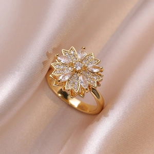 Exquisite golden flower ring with clear zircon pave setting on elegant satin background