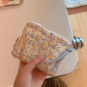 Close-up of floral print cotton pouch with simple wish label and light blue rope zipper