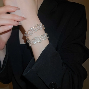 Macro detail of multilayer pearl and rhinestone bracelet set on a black blazer sleeve