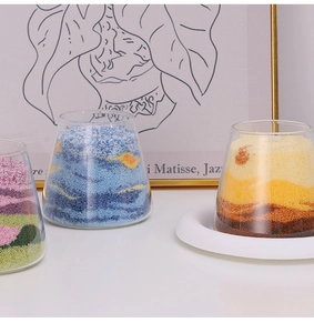 Artistic layered sand candles in transparent glass cups with colorful wax granules