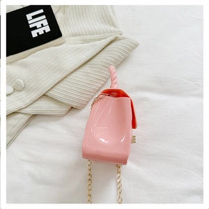Detail of pink PVC quilted bag with golden chain and twisted handle on white fabric