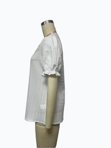 Detail of white short sleeve shirt with vertical stripe texture and ruffled cuffs