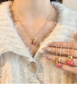 Detail of 18k gold plated lucky pouch pendant necklace with pink heart charms on model