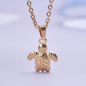 Macro shot of gold stainless steel turtle pendant necklace with detailed shell texture