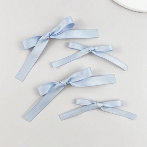 Set of four light blue satin ribbon bow hair clips in two sizes on a grey surface