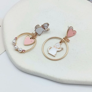 Detail of asymmetric cat heart earrings with pearls and pink crystals on white stone