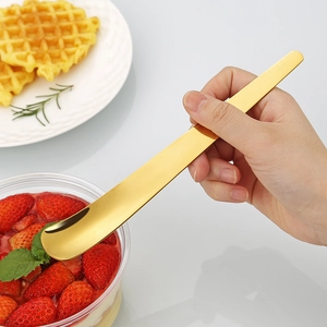 Langer goldener Edelstahllöffel für Eiscreme, präsentiert mit Erdbeeren und Waffeln
