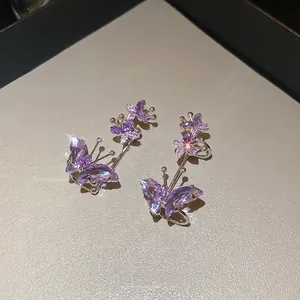 Elegant purple zircon butterfly ear clips in silver setting displayed on beige texture