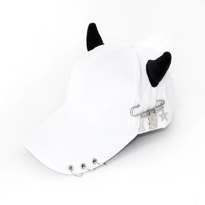 Close-up of white baseball cap with plush devil horns and metallic gothic charms