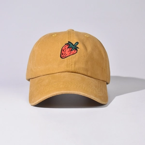 Dettaglio del ricamo a fragola sul cappellino da baseball in cotone giallo zenzero