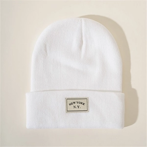 Close-up of white knitted beanie with New York N.Y. embroidered patch detail