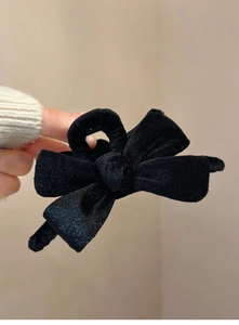 Close-up of a large black velvet bow hair claw clip with delicate pearl accents