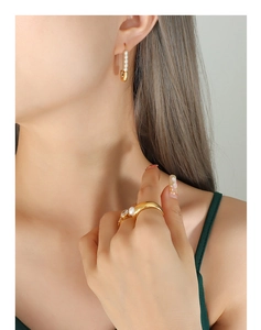 Detail of paperclip earring with pearls and matching gold ring worn by a model