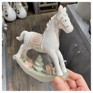 Detail of Christmas white rocking horse resin ornament with pink saddle and knit texture