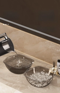 Modern smoke gray transparent washbasin set on marble counter with ice and hot water