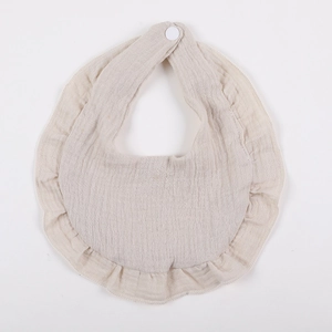 Detailed macro of a beige cotton crepe baby bib featuring ruffled edges and snap button