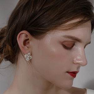 Detail view of a camellia flower stud earring on ear with white enamel petals