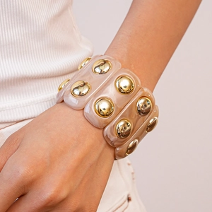 Detail of chunky acrylic marble bracelet with large gold dome studs on a model