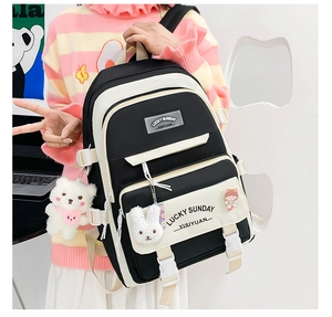 Detail view of the black and beige spliced backpack with a cute bear plush pendant