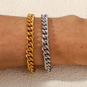 Detail view of high-polish gold and silver plated Cuban link bracelets on a wrist