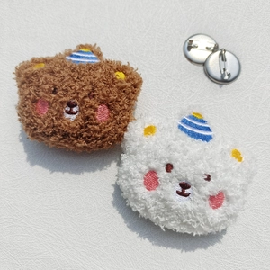 Detailed view of plush bear brooches in brown and white with striped party hats