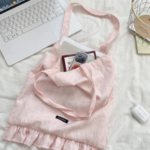 Detailed view of pink textured canvas tote bag with ruffled edges and branded woven label