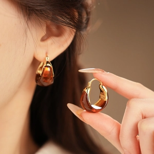 Detailed view of teardrop amber resin earrings with gold-plated metal hoops on model