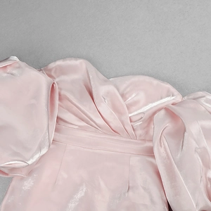 Detail of pink satin off-shoulder dress featuring twisted knot neckline and puff sleeves